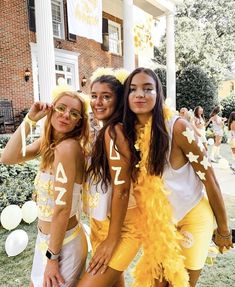 three girls dressed in yellow and white posing for the camera