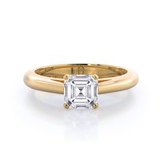 a rose gold ring with an emerald cut diamond in the center, on a white background