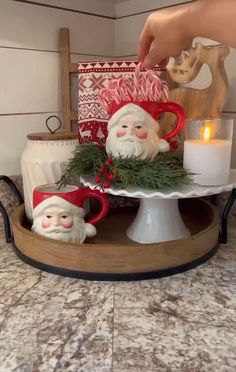 a tray with santa clause figurines on it and candles in the back ground