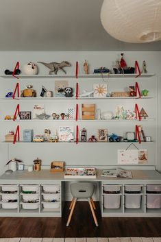 the shelves are filled with toys, books and other items in white containers on wooden flooring