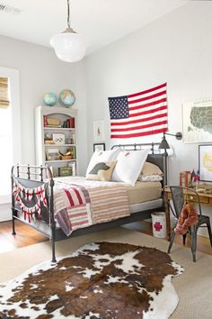 an american flag hanging on the wall above a bed in a room with white walls