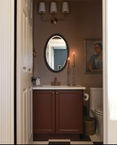 a bathroom with a sink, mirror and toilet in it's doorway way to another room