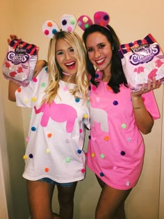 two women dressed in pink and white are posing for the camera while holding candy bags