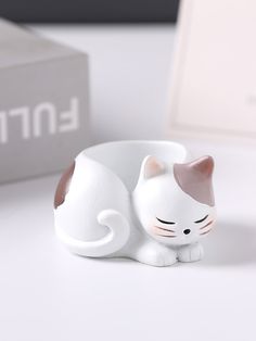 a white cat figurine sitting on top of a table next to a box