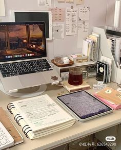 an open laptop computer sitting on top of a desk next to a pile of books