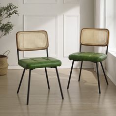 two green chairs sitting next to each other on top of a hard wood floor in front of a white wall