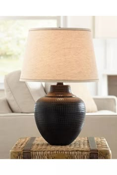 a table lamp sitting on top of a wicker box in front of a couch