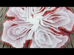 a red and white flower sitting on top of a wooden table