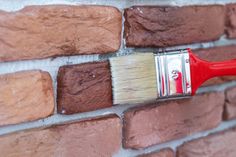 a red paint brush on top of a brick wall