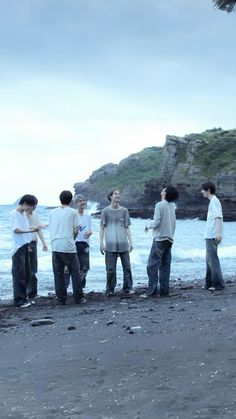 four men standing on the beach talking to each other