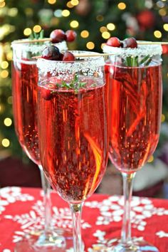 two glasses filled with wine sitting on top of a table next to a christmas tree