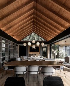 a large wooden dining room table surrounded by gray chairs and white lamps hanging from the ceiling