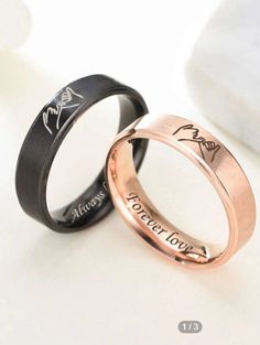 two wedding rings with engraved names on them, one is black and one is rose gold