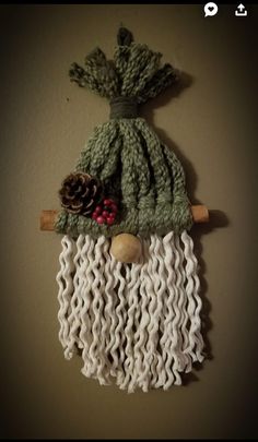 a knitted bag hanging on the wall with pine cones and other things in it