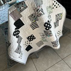 a white and black quilt sitting on top of a kitchen floor next to a table