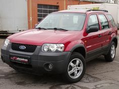 a red ford escape is parked in a parking lot next to a brick building and white truck