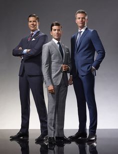 three men in suits posing for the camera