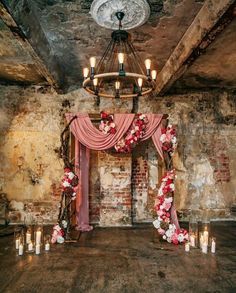 an old room with candles and flowers on the floor in front of a chandelier