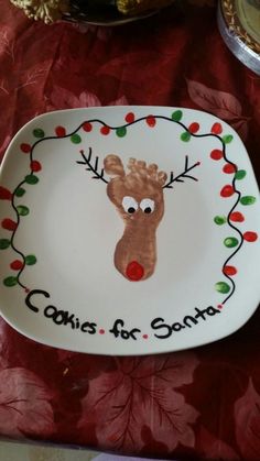 a white plate with a reindeer's face painted on it and the words carols for santa