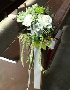 a bouquet of flowers sitting on top of a wooden bench in front of a pew