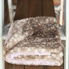 two blankets are folded on top of each other near a wooden table with chairs in the background