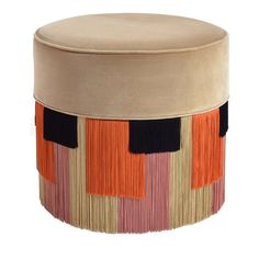 a round ottoman with multicolored stripes and fringes on the bottom, sitting in front of a white background