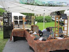 an outdoor market area with tables and chairs under a tent that has many items on it