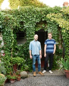 two men standing in front of a green house