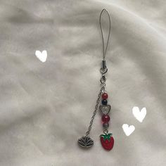 an apple charm is attached to a chain on a white sheet with hearts in the background