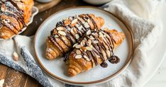 two croissants with chocolate drizzled on them and almonds