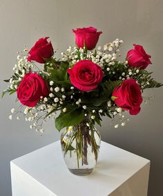 a vase filled with red roses and baby's breath