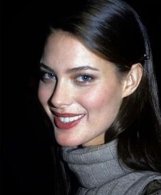 a close up of a person wearing a turtle neck sweater and smiling at the camera