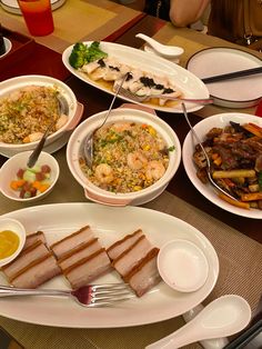 a table topped with plates and bowls filled with different types of food next to utensils