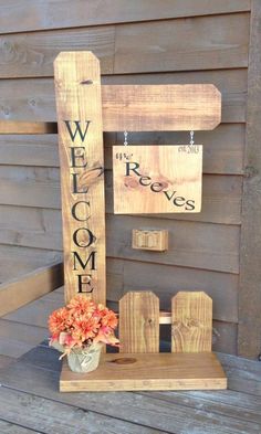 a wooden welcome sign sitting on top of a wooden bench next to a potted plant