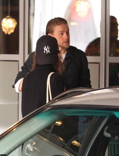 a man and woman standing next to each other near a car