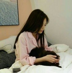 a woman sitting on top of a bed holding a cat