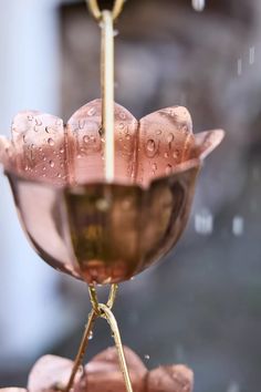 a pink glass vase sitting on top of a metal stand with water droplets all over it