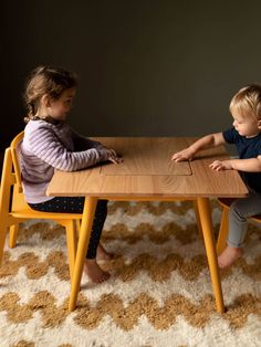 two children sitting at a table playing with each other