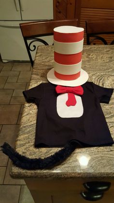 a cat in the hat costume on top of a t - shirt sitting on a counter