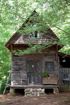 an old log cabin in the woods with a porch and steps leading up to it