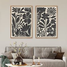 two black and white paintings on the wall above a gray couch in a living room