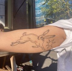 a person with a tattoo on their arm that has an image of a rabbit running