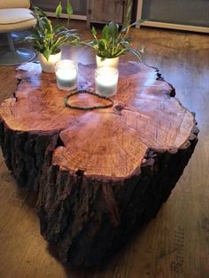 two candles are sitting on top of a tree stump in a living room with wood flooring