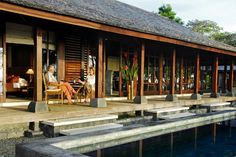 two people sitting on chairs in front of a wooden building next to a swimming pool