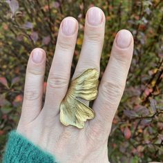 Statement brass gingko leaf ring, Bold rings for her, Adjustable size ginko biloba ring, Unique bohemian jewelry, Gift for plant lover. The ring is crafted based on a real Ginko biloba leaf. It is made of high-quality brass. It features an adjustable size. The band is open, allowing for size adjustments. The size of the leaf is 5.7 cm in height, and the width including the stem, which forms part of the band, is approximately 6 cm / 2.24 inches x 2.36 inches. It fits best sizes US 5-9 / EU 8-20 (48mm -60mm). It can be adjusted to larger sizes by a few more, however, in this case, there may be a gap between the ends of the petal, although it does not prevent wearing the ring. It's a matter of preference. If you know your size, please provide it when placing your order, and we will adjust the Handmade Gold Flower Ring Nature-inspired, Handmade Gold Flower Ring, Nature-inspired, Ginkgo Leaf Ring, Gingko Earrings, Ginko Earrings, Gingko Leaf Jewelry, Ginko Necklace, Unique Gold Wing-shaped Jewelry, Ginko Biloba