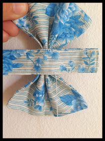 a person is holding up a blue and white flowered fabric bow on a wall