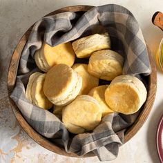 a wooden bowl filled with cookies next to two plates