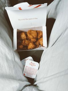 a box filled with donuts sitting on top of a bed next to a pillow