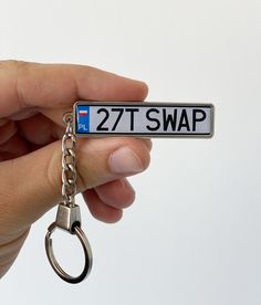 a hand holding a metal key chain with a license plate on it that says 27t swap