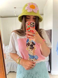 a woman taking a selfie in front of a mirror wearing a hat and t - shirt with a dog on it